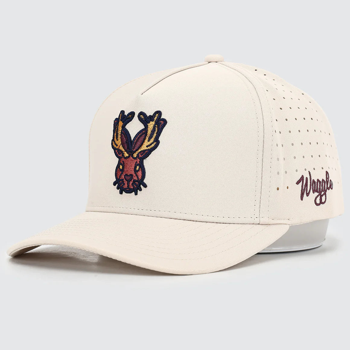 Beige cap with embroidered design and 'Waggle' branding on a light gray background