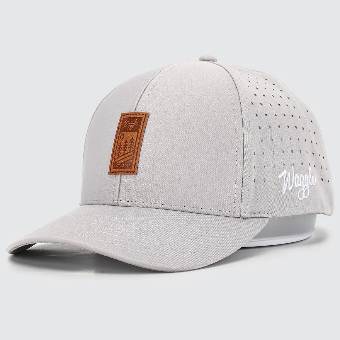 Light gray baseball cap with brown leather patch and white WAggle logo on a light gray background