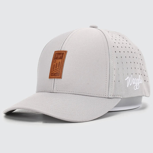Light gray baseball cap with brown leather patch and white WAggle logo on a light gray background